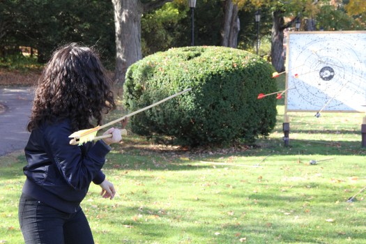 Student in Human Origins course throws a spear using an atlatl or spear thrower. The target in the distance has already been hit with other darts.