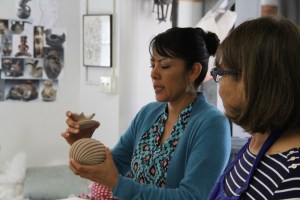 Image of Mia Toya with pottery vessel, Maxine Toya looks on.