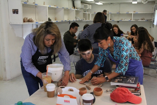 Image of Pueblo potters Dominique and Mia Toya working with a high school student.