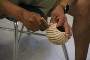 Image of Ward helping to sand the spiral ribs on a butterfly swirl bowl.