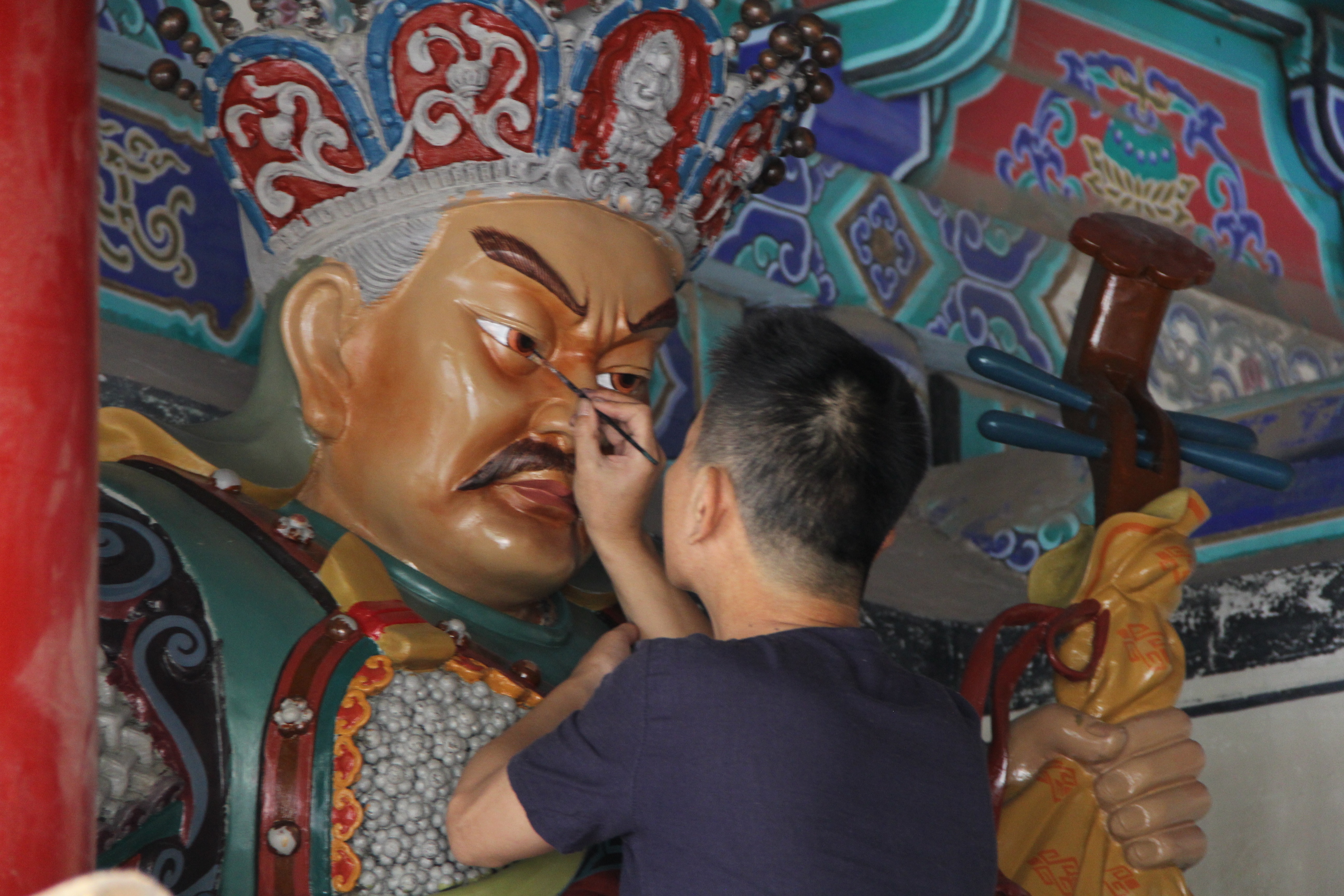 Image of an artist restoring the giant statute of a Buddhist immortal at the Shaolin Monastery.