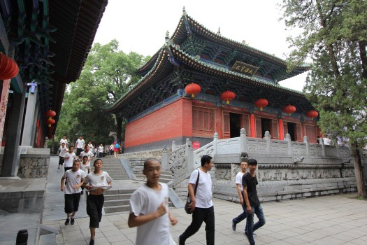 Image of Gong Fu students running past the Shaolin Temple buidlings.
