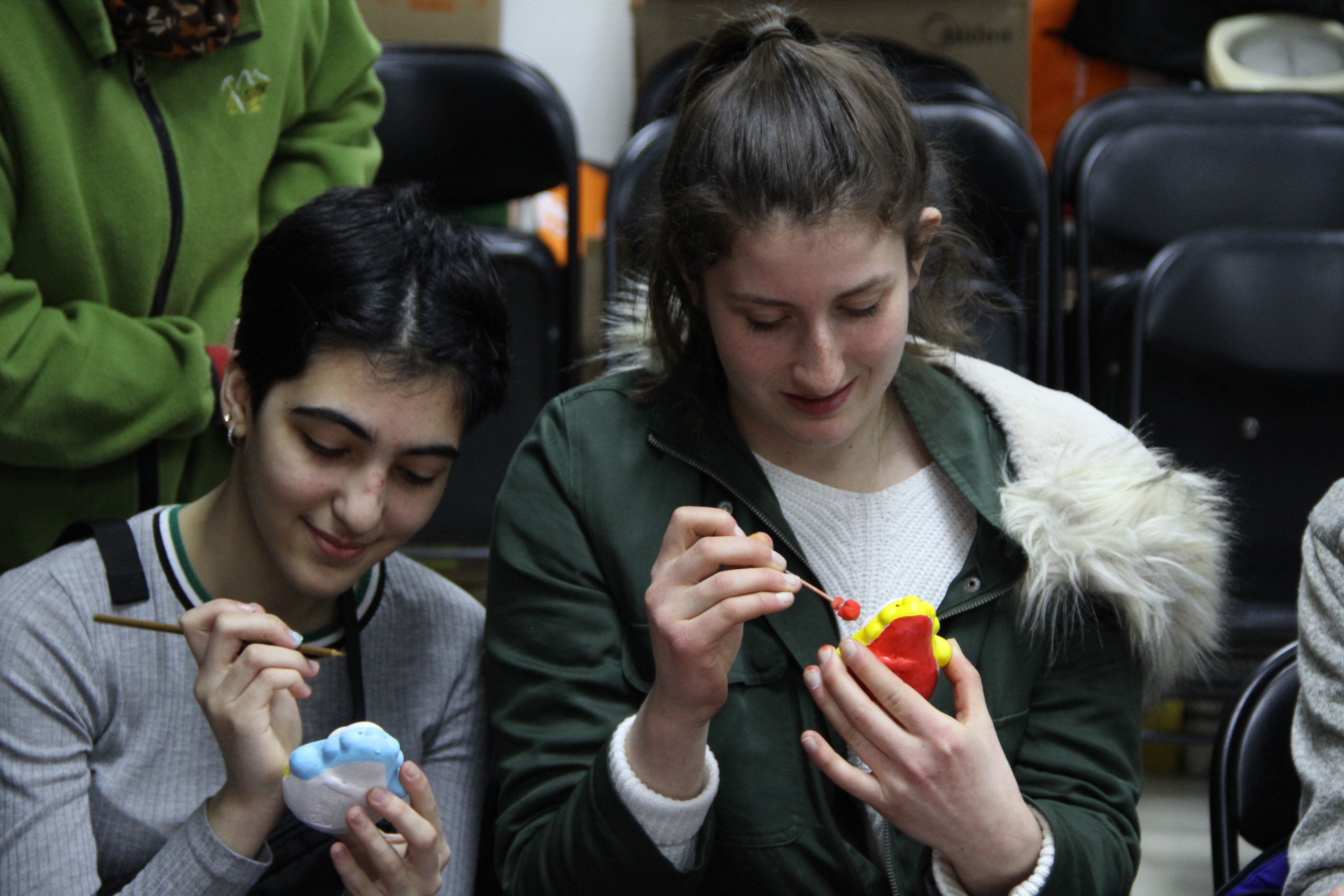 Two students paint ceramic rabbit figurines.
