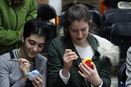 Two students paint ceramic rabbit figurines.