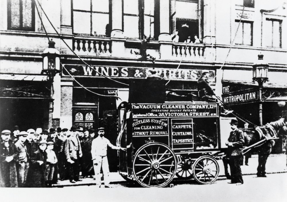 Photograph of Booth's vacuum cleaner on city street, with horse harnessed and people gathered.