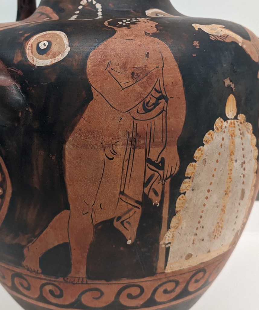 close up image of a painting on an ancient greek vessel, showing a man wearing a laurel wreath and leaning on a staff